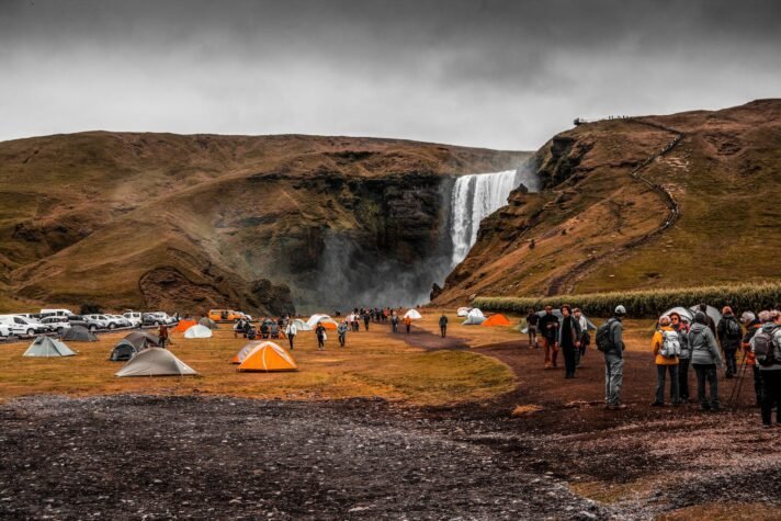 people standing on camping site near waterfalls